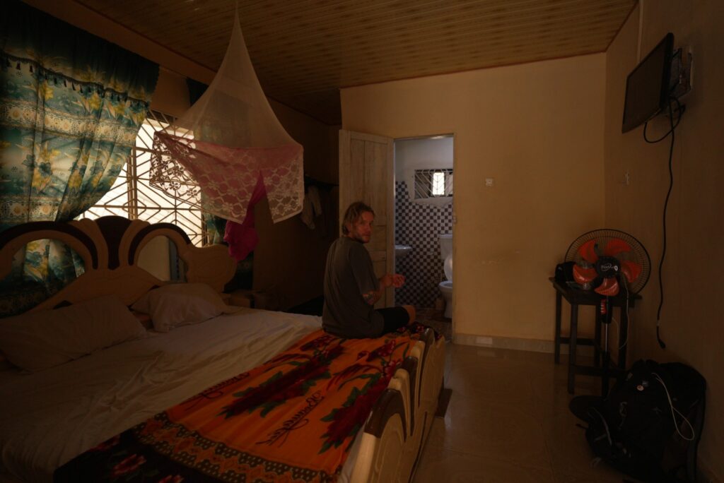 Vīrietis sēž gultā tumši sarkanā istabā