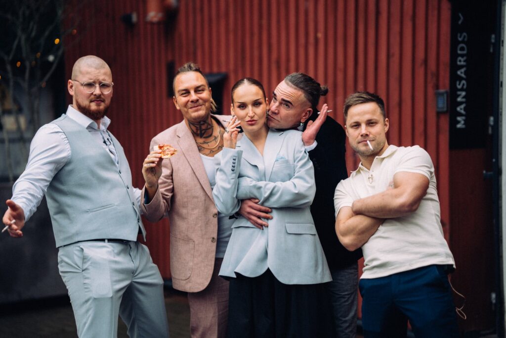 cilvēki stāv ārā, smēķē un ģērbjas elegantās drēbēs