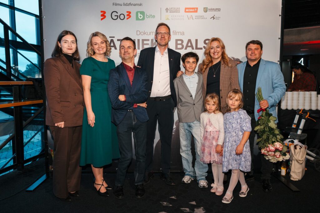 daudzi cilvēki stāv filmas pirmizrādē
