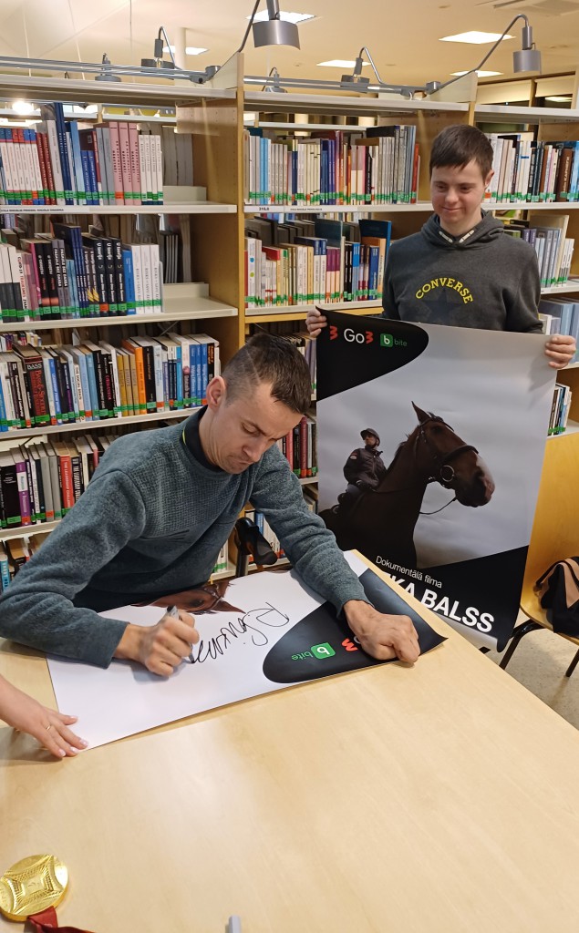 vīrietis dod autogrāfu bērnam
