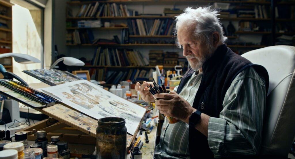 vecs vīrs sēž un zīmē
