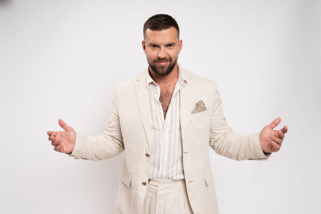 vīrietis uzvalkā, izplešot rokas