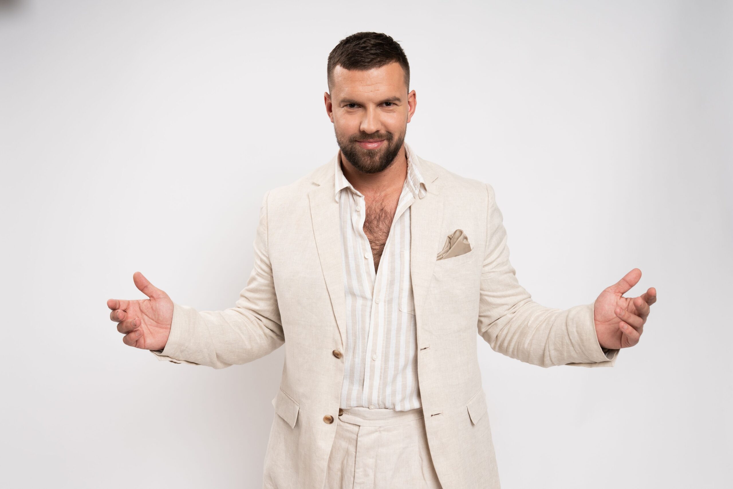 vīrietis uzvalkā, izplešot rokas