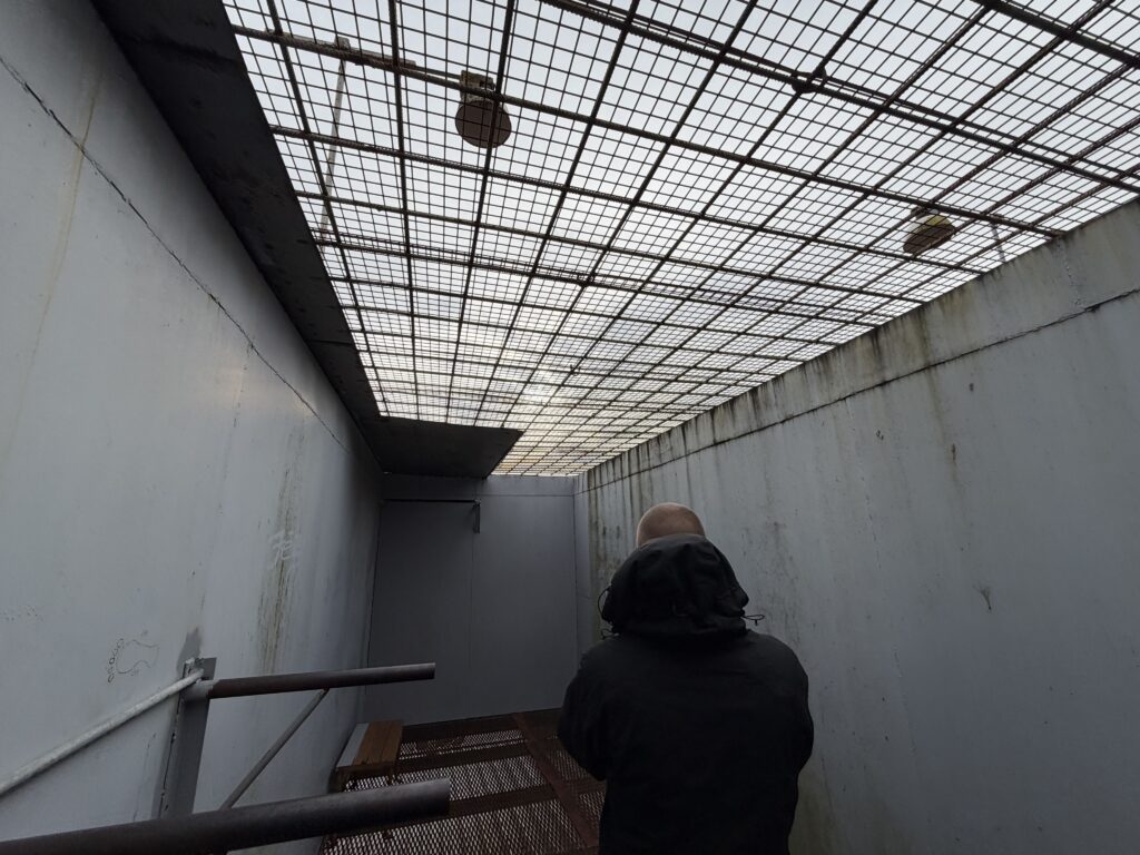 vīrietis skatās uz cietuma kameru